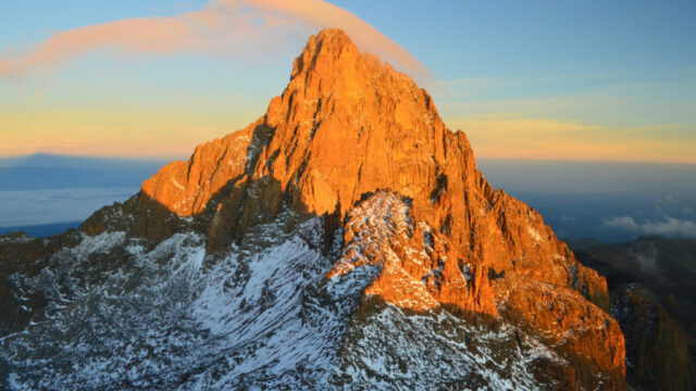 A majestic mountain peak bathed in golden sunlight with snow-covered slopes. Perfect for east Africa safari tours.