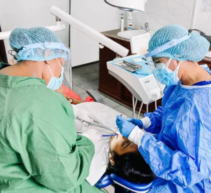 Two medical professionals are performing a dental procedure on a patient.