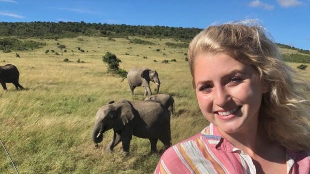 A person is enjoying a safari experience with elephants in the background. It appears to be an east Africa safari tour.