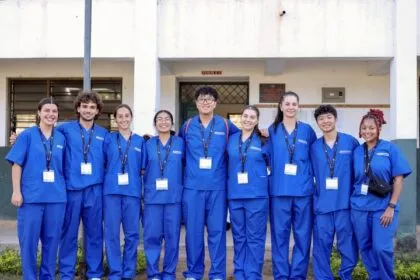Group of physician assistant and pre-PA interns in matching blue scrubs smiling outside a clinical training facility.