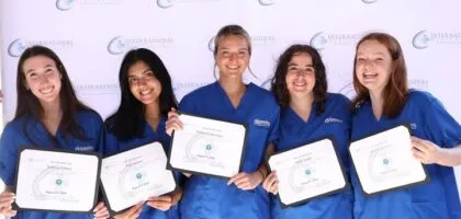 A group of people wearing blue scrubs are holding certificates, possibly related to medical internship achievements.