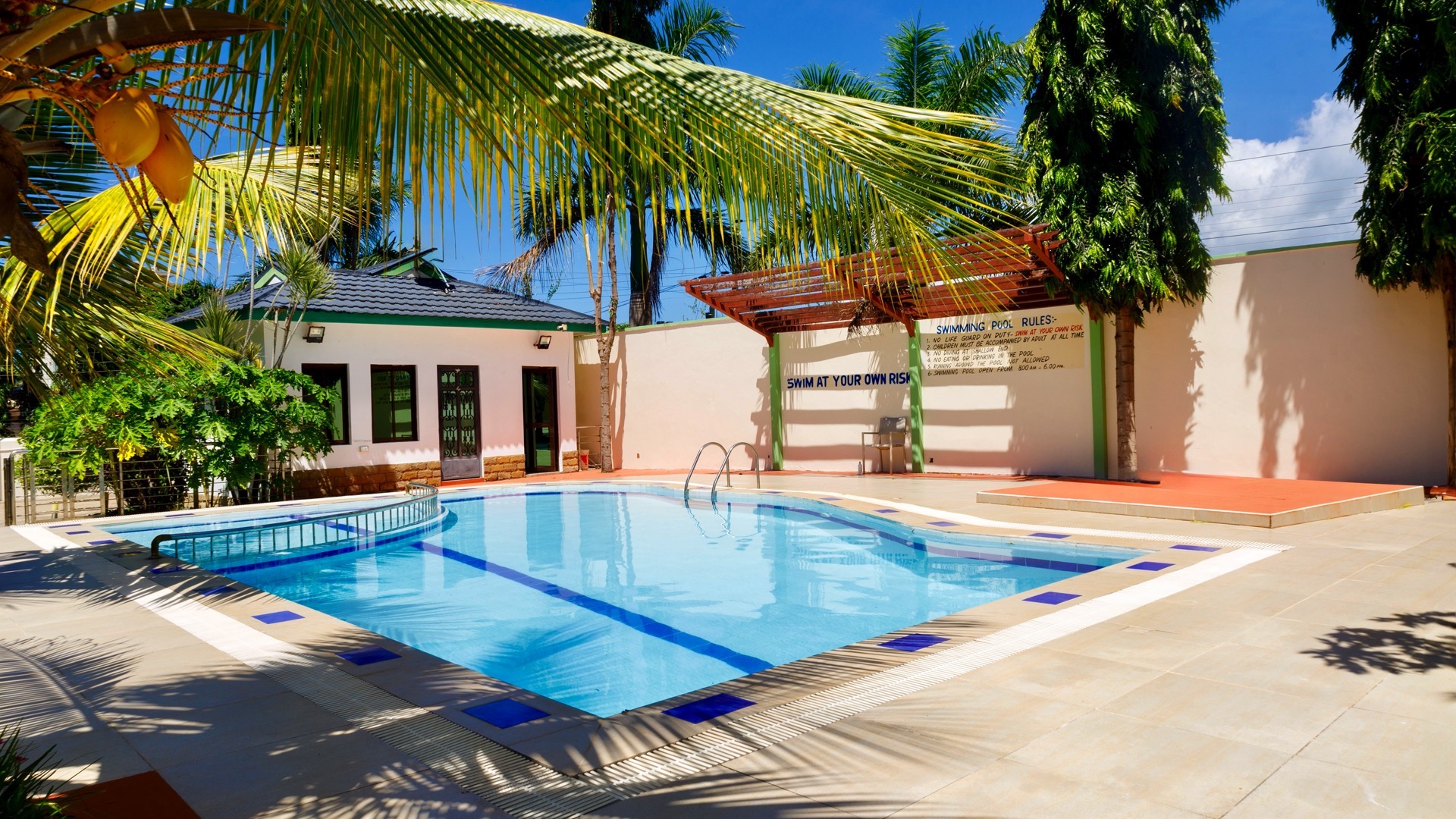 A pool with palm trees, a building, and a 