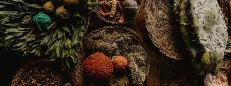 Baskets filled with natural fibers, wool, and dyed yarn in earthy tones.