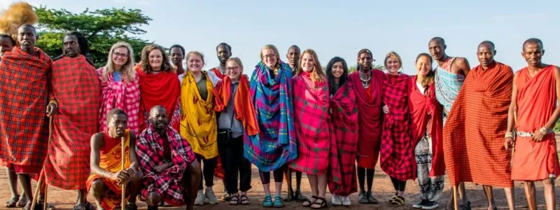 Group of adults standing together, dressed in colorful traditional garments during a cultural exchange experience.