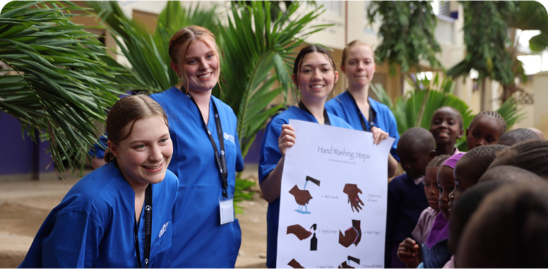 People in blue uniforms teach children about handwashing.