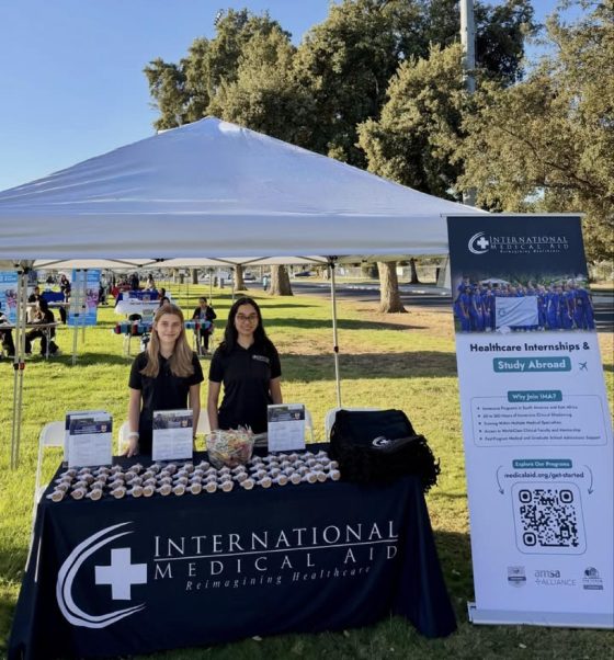 Two IMA representatives behind the International Medical Aid table and banner on Hutchison Field